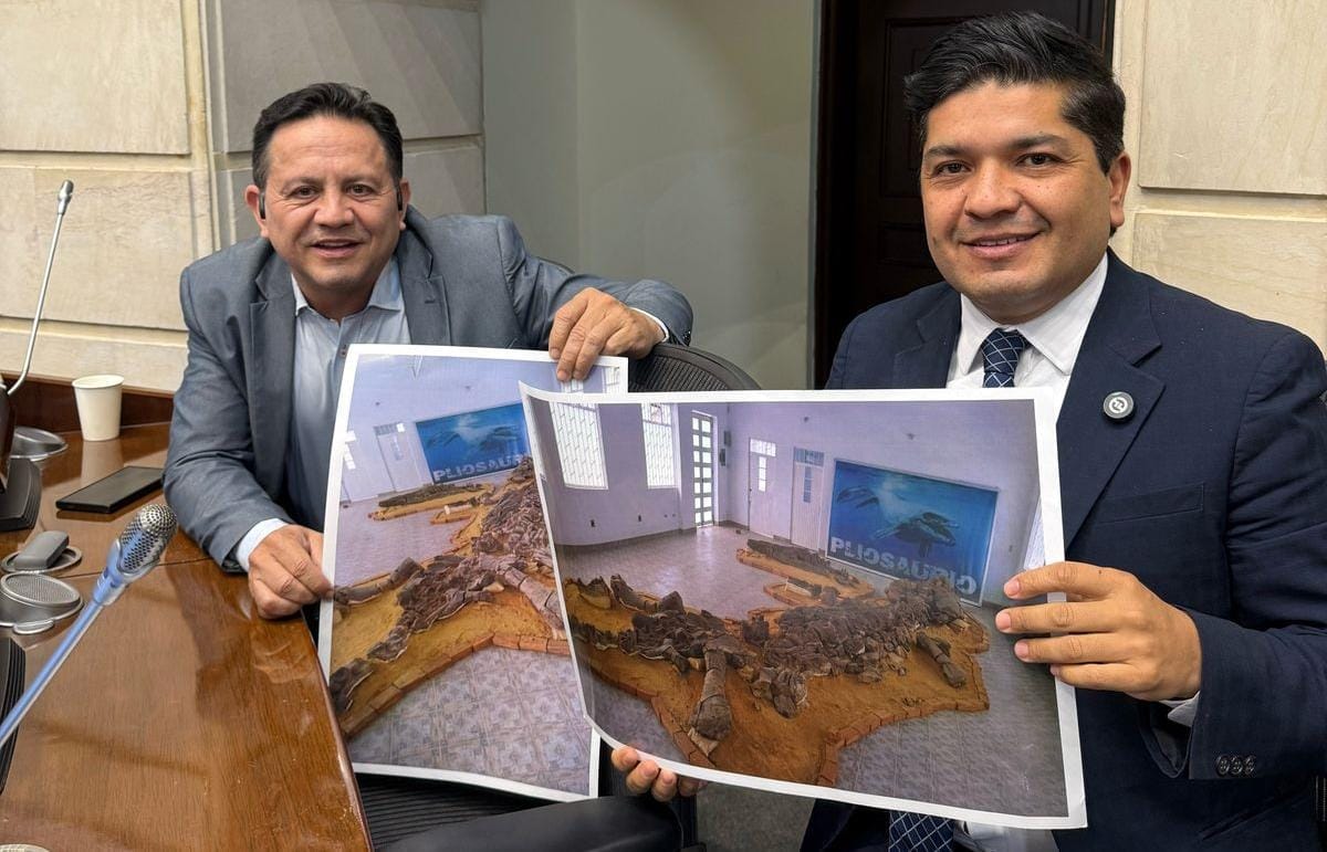 Fósil del Pliosaurio exhibido en un museo con paisaje de Sáchica, Boyacá, al fondo, destacando su patrimonio paleontológico.